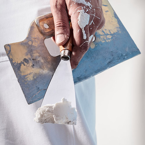 Close up Of Professional Workman Hand holding Putty Knife with Plaster